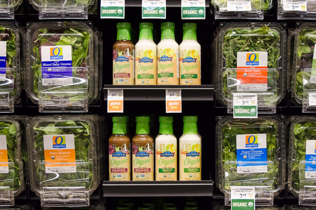 retail display of produce clamshells and bottles of salad dressing