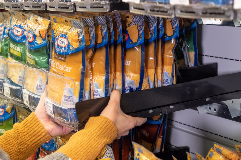 Hands adjusting a shelf rail to front bags of shredded cheese