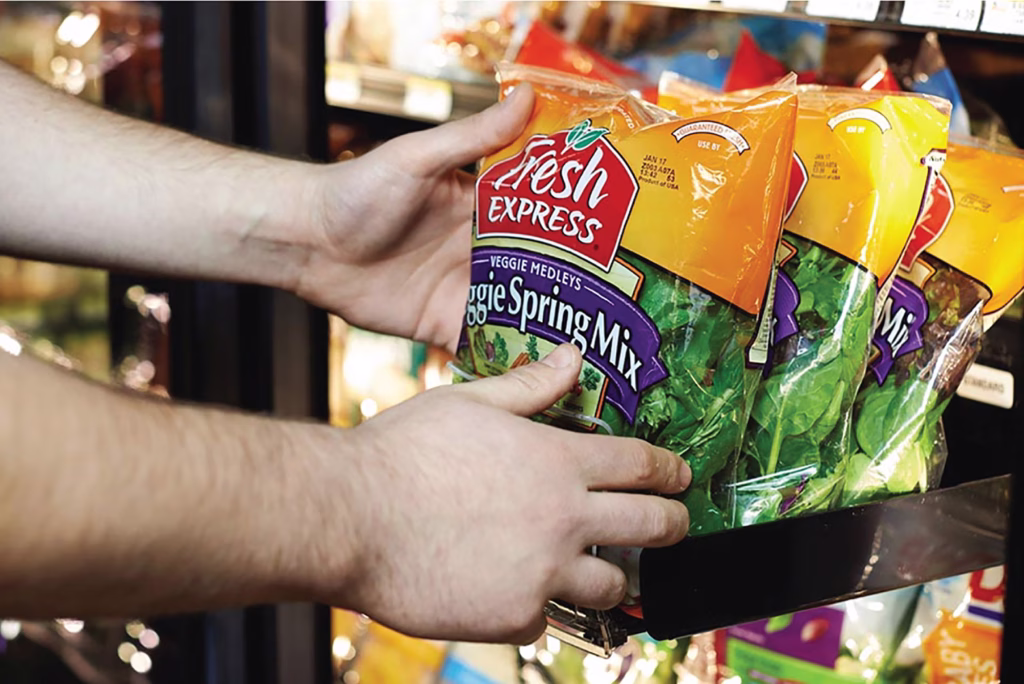 hands adjusting SpaceGrid II system holding bagged salads